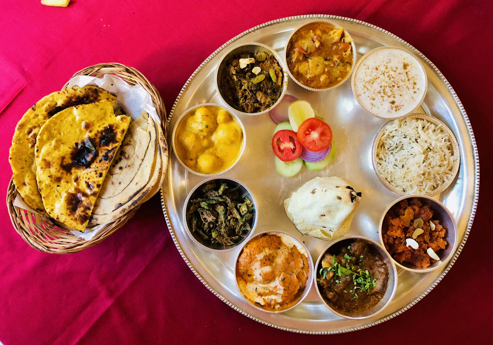 A home-style Indian thali: dal, sabzi, rice, raita and rotis on a steel plate.